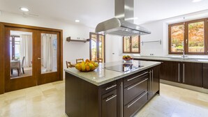 Une cuisine moderne dotée d’un grand îlot central, de meubles en bois et d’une hotte aspirante en acier inoxydable.
