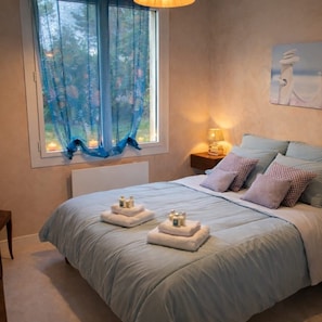 A bedroom with a large bed, a window with blue curtains, a bedside table with a lamp, and a painting on the wall. - Big House 10/ 13 persons ***3 keys 150 meters from the beach (La Tranche-Sur-Mer)