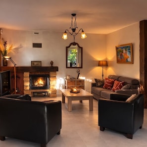 A living room with a fireplace, two sofas, a coffee table, and a chandelier. - Big House 10/ 13 persons ***3 keys 150 meters from the beach (La Tranche-Sur-Mer)