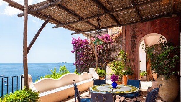A terrace with a table and chairs, overlooking the sea.