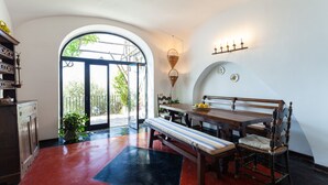 A dining area with a wooden table, bench, and chairs, a potted plant, and a wall-mounted light fixture.