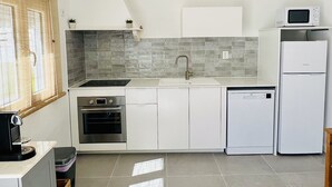 A modern kitchen with white cabinets, a built-in oven, a microwave, and a dishwasher. - Salty Soul Beach House (Costa da Caparica)