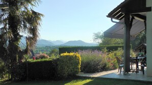 Un jardin offrant une vue sur les montagnes, une pergola et un espace patio aménagé avec des sièges d’extérieur.