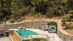 Ein Poolbereich mit Steinmauern, Sitzgelegenheiten im Freien und einem Baldachinbett.