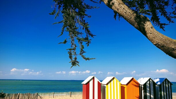A row of colorful beach huts with a sandy beach and ocean in the background. - Seafront not overlooked, experience the postcard from the inside! (La Brée-Les-Bains)