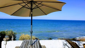 An outdoor area with a beige umbrella, a wooden deck, and a view of the ocean. - Seafront not overlooked, experience the postcard from the inside! (La Brée-Les-Bains)