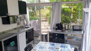 A compact kitchen with a built-in oven, a sink, and a small dining area with a table. - Seafront not overlooked, experience the postcard from the inside! (La Brée-Les-Bains)