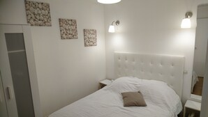 A bedroom with a white bed, a headboard, and three wall-mounted light fixtures. - Seafront not overlooked, experience the postcard from the inside! (La Brée-Les-Bains)