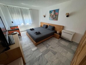 A bedroom with a bed, a desk, a chair, a TV, a painting, and a window with curtains. - Sunny Villa - Luxury private property with outstanding heated pool! (Kosharitsa)