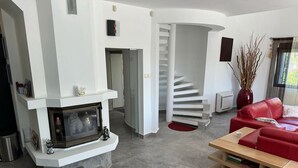 A modern living room with a fireplace, a red sofa, a wooden coffee table, and a spiral staircase. - Sunny Residence - Luxury private property with outstanding heated pool! (Kosharitsa)