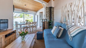 Una sala de estar moderna con un sofá azul, techo de madera y chimenea de piedra.