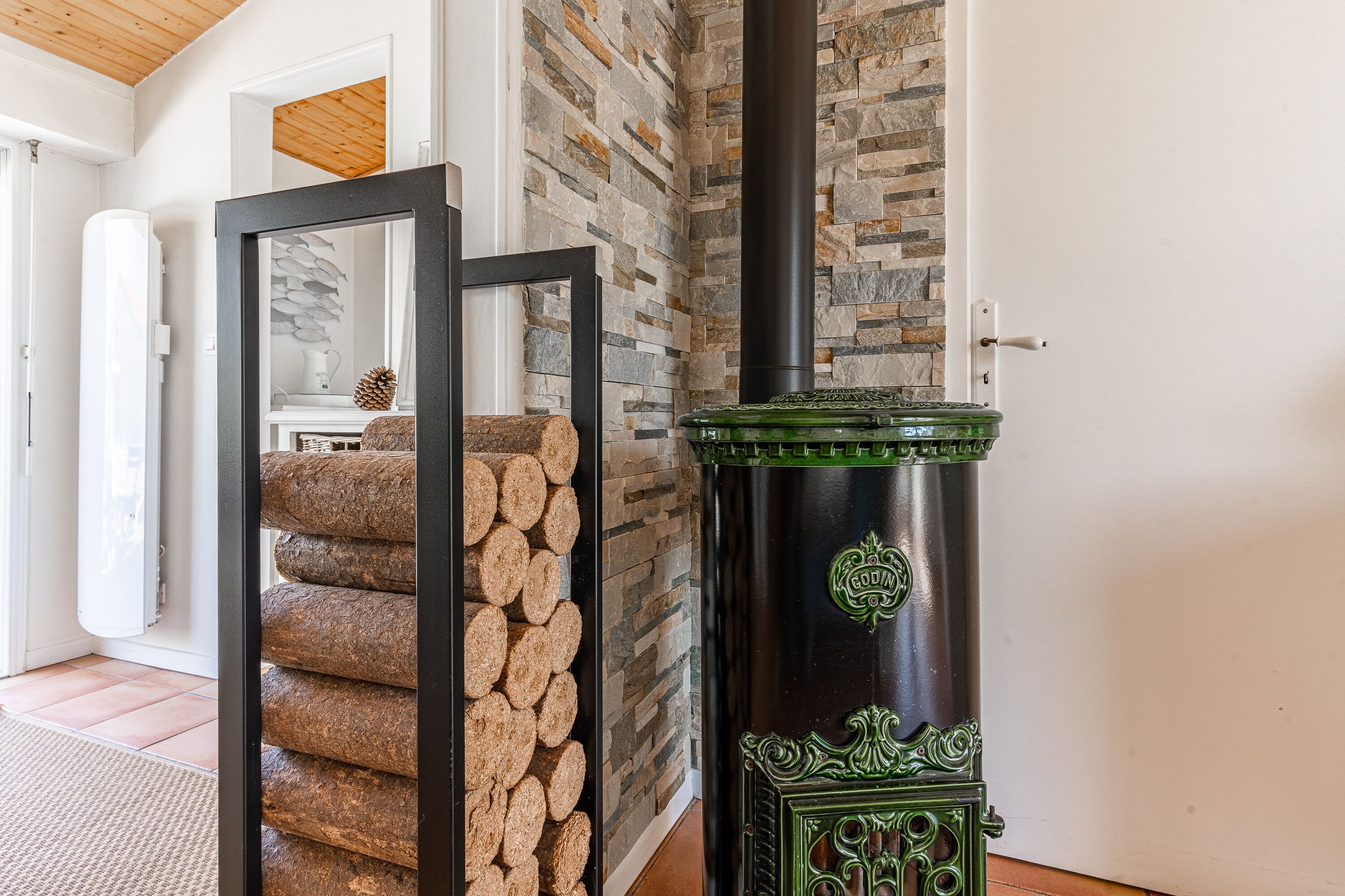 Una habitación con pared de piedra, techo de madera y estufa verde.