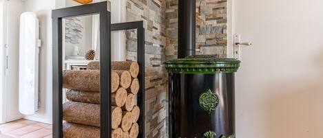 Una habitación con pared de piedra, techo de madera y estufa verde.