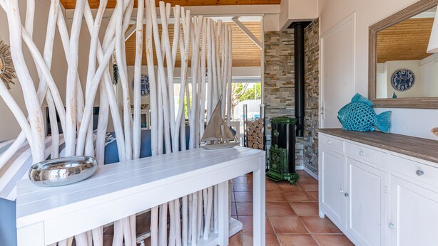 Una cocina con armarios blancos, techo de madera y pared de piedra.