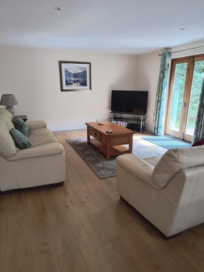 A living room with a sofa, a coffee table, a television, and a window with curtains. - set in stunning countryside and only 1 mile from the surfing beach of Bantha (kingsbridge)