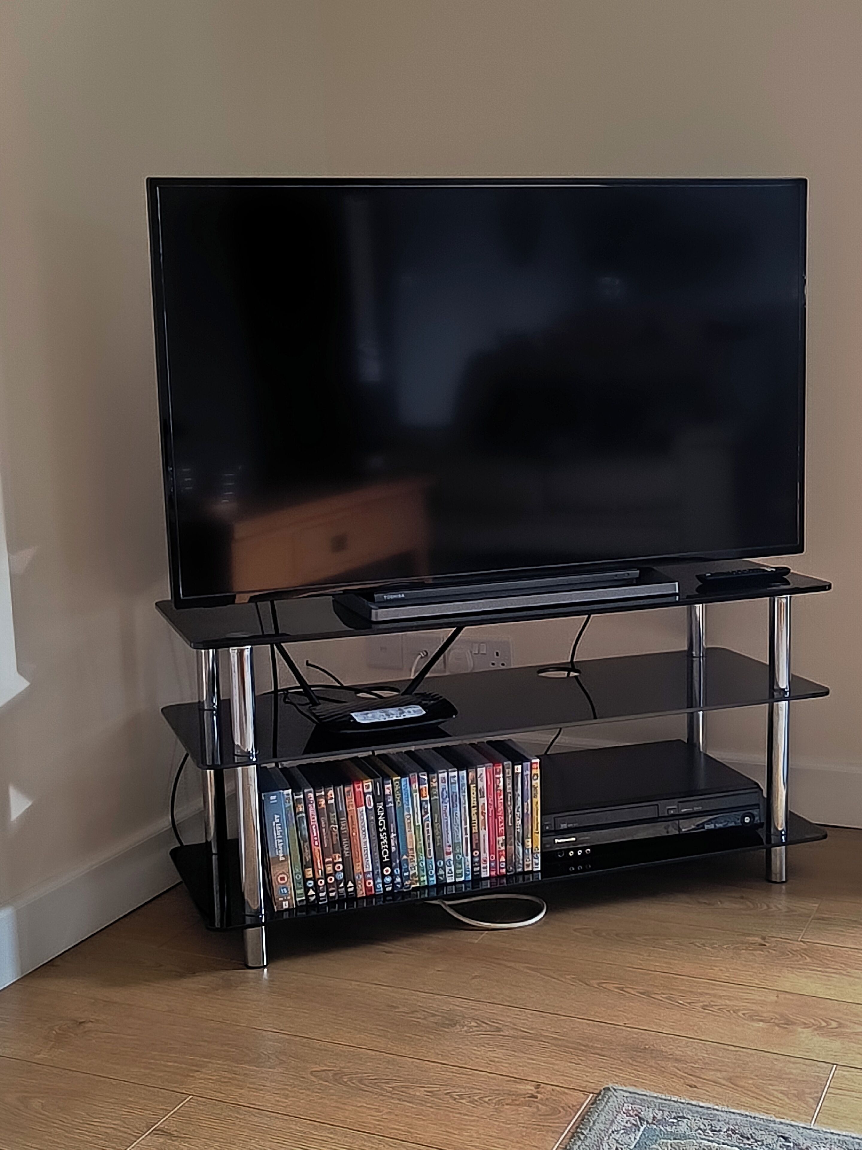 Een televisiesetup met een flatscreen-tv, een mediaplank en een dvd-speler.