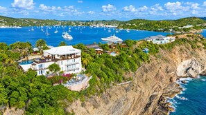 Una propiedad costera con una casa grande, piscina y vista al mar con barcos.