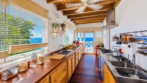 A kitchen with wooden cabinets, a central island, and a view to the outside.