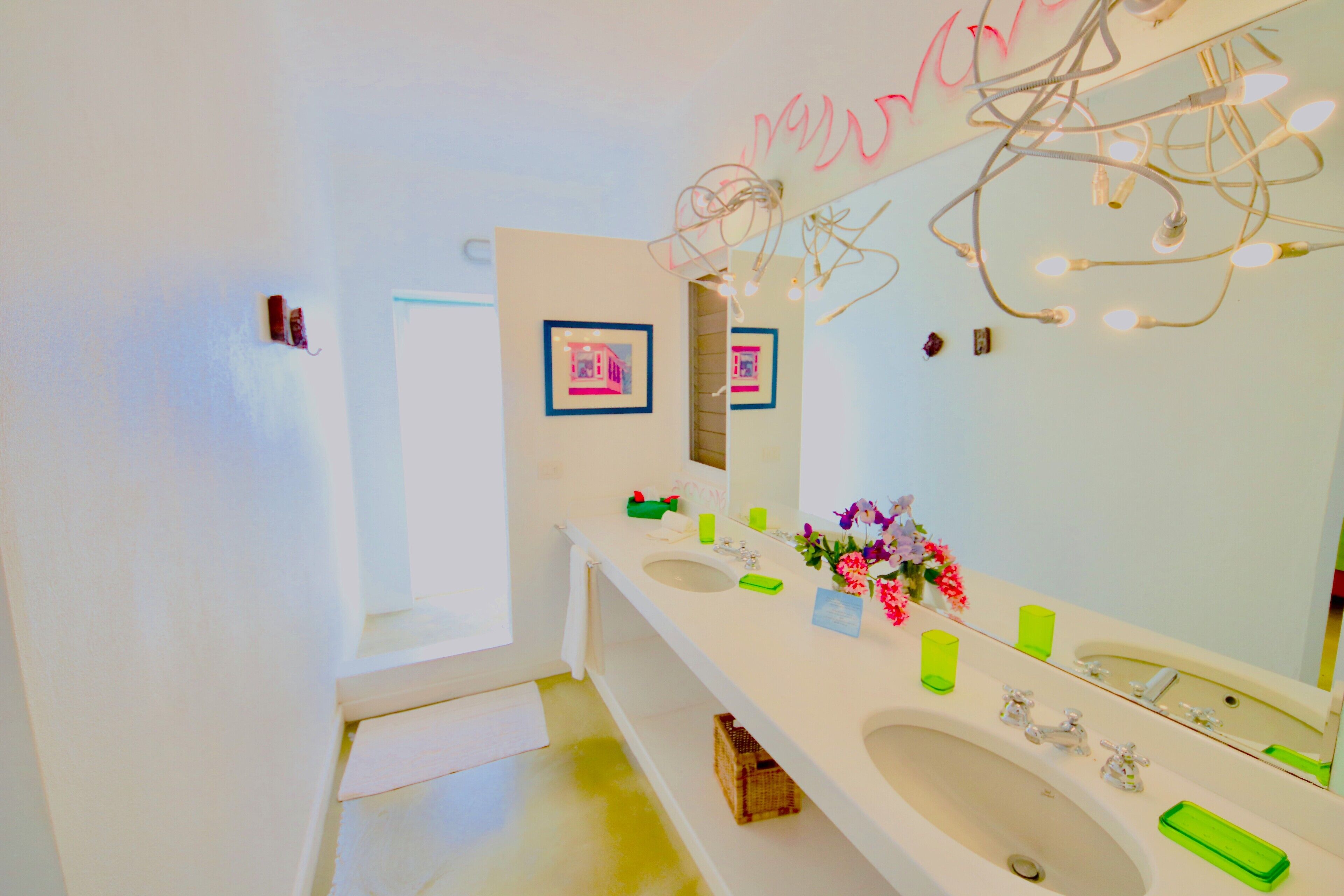 Ein modernes Badezimmer mit zwei Waschbecken, einem großen Spiegel und dekorativer Beleuchtung.
