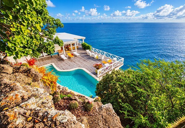 A resort with a pool, lounge chairs, and a view of the ocean.