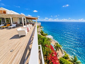 Una terraza de madera con sillones de descanso con vistas al mar azul y transparente.