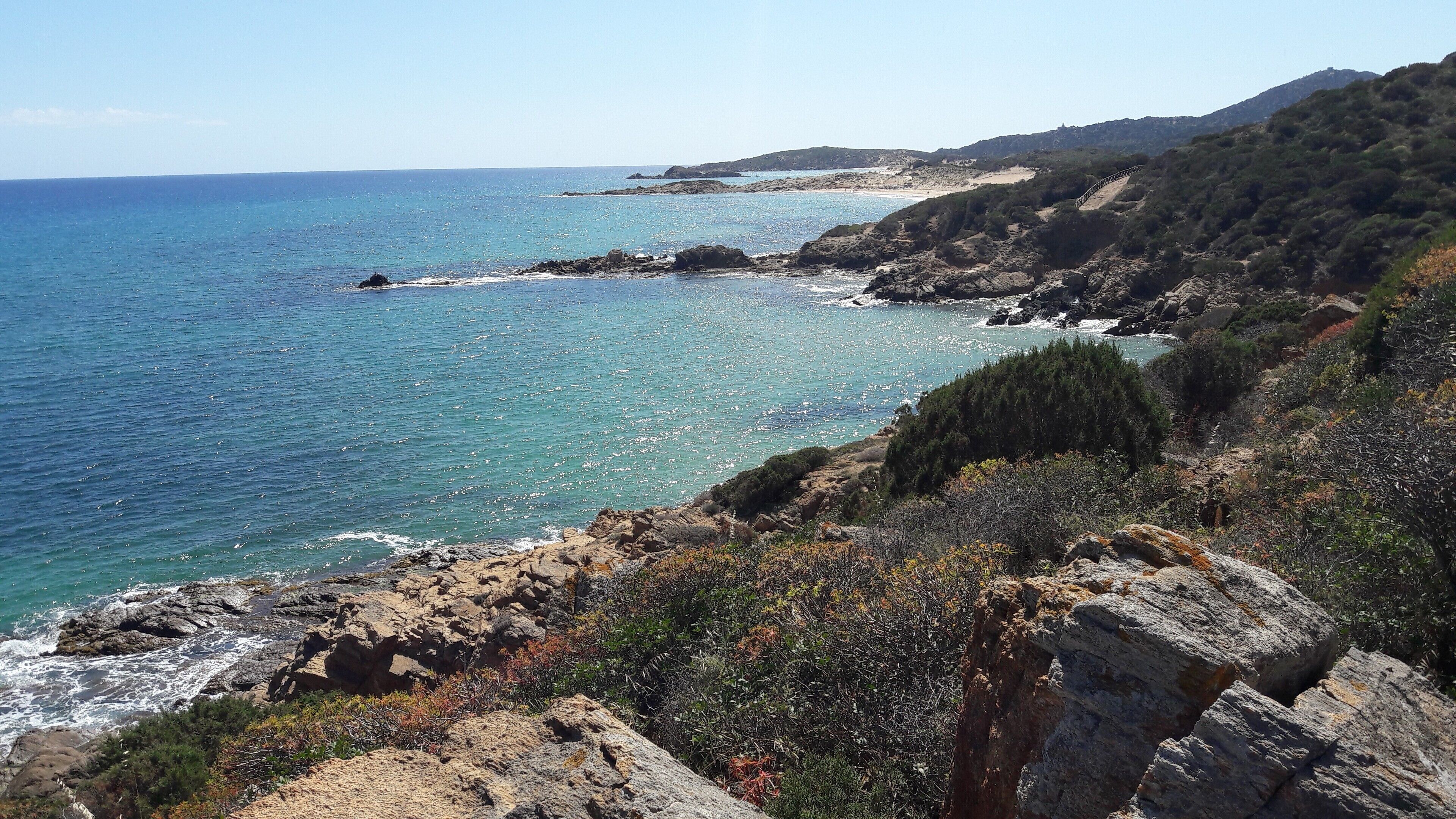 A coastal landscape with rocky terrain and a clear view of the sea.