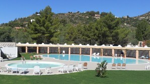 A swimming pool with lounge chairs and a grassy area.