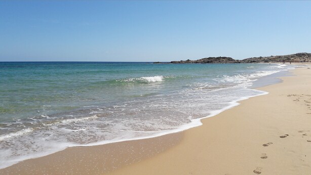 A sandy beach with gentle waves and a clear sky.