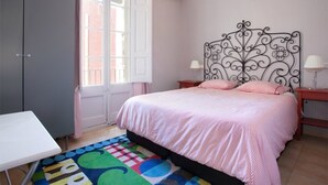 A bedroom with a bed, a desk, a chandelier, and a window with curtains. - SANT ANTONI, nice, silent and central located vacation rentals in Barcelona (Barcelona)