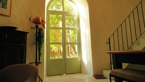 Une pièce avec une porte verte, un escalier, un tableau encadré au mur et un vase rempli de fleurs.