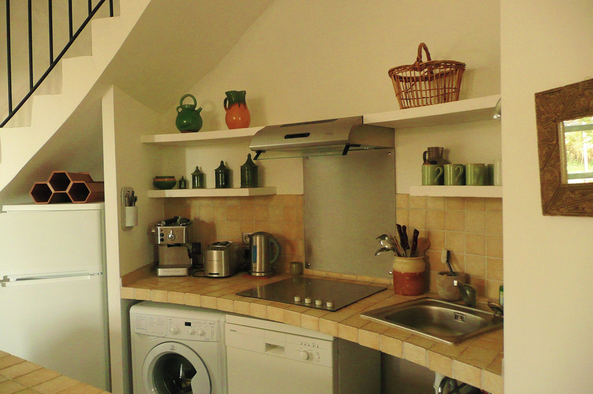 Een kleine keuken met een wasmachine, een fornuis en een spoelbak.