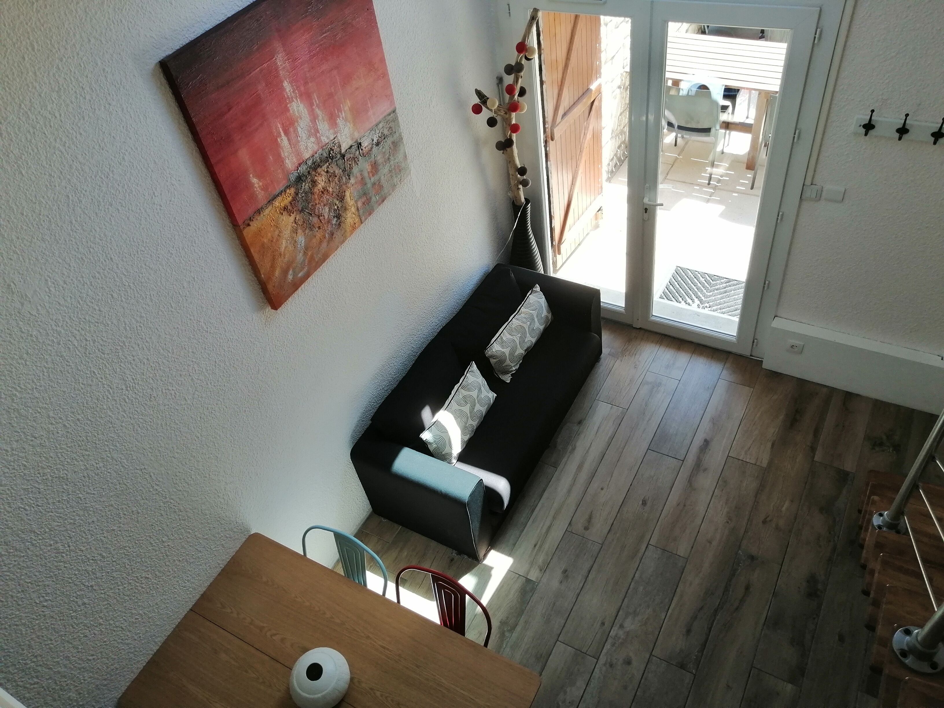 A modern living room with a black sofa, a wooden coffee table, and a red abstract painting on the wall.