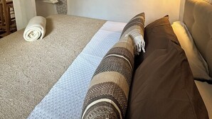 Un dormitorio con cama, estante en la pared con toallas dobladas y un cartel que dice "BEACH".