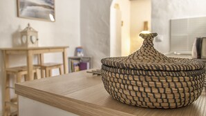 Una cesta tejida sobre una mesa de madera en una habitación con pared de mármol y un cuadro.