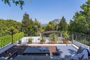 A deck with outdoor furniture, a pergola, and potted plants.