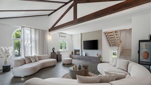 A spacious living room with a large L-shaped sofa, a round coffee table, and a flat-screen TV mounted on the wall. - Villa PROVOS with 40m2 private pool, sauna, max 8 person, 7km from sandy beach (TUGARE)