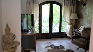 A living room with a television, a stone Buddha statue, a sofa, and a large window with curtains. - Villa With Private Pool And Jacuzzi (Bay of Kotor)