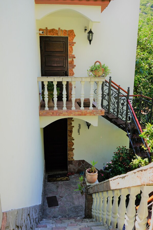 A two-story building with a balcony, a staircase, and a door.