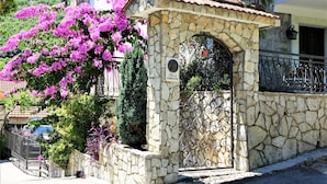 A stone villa with a wrought iron gate, surrounded by lush greenery and flowering plants. - Villa With Private Pool And Jacuzzi (Bay of Kotor)