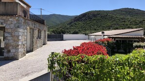 Un edificio de piedra con una reja metálica, un camino de grava y vistas a la montaña.