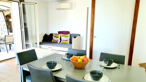 Un comedor con una mesa dispuesta para cuatro personas, sillas y un frutero.
