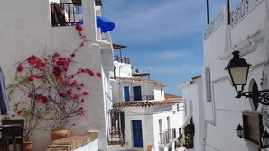 Une rue étroite bordée de bâtiments blancs, avec une porte bleue et une enseigne indiquant un restaurant.