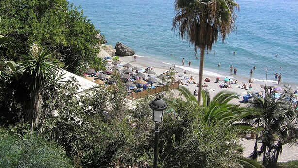 Une plage avec des parasols et des gens.