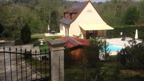 Une maison avec une piscine, des panneaux solaires et un jardin clôturé.