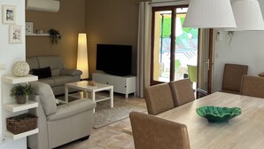Un salon moderne comprenant un canapé, un téléviseur et un coin repas avec des chaises et une table.