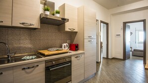 Una cocina moderna con electrodomésticos de acero inoxidable, encimera de madera y armarios de madera clara.