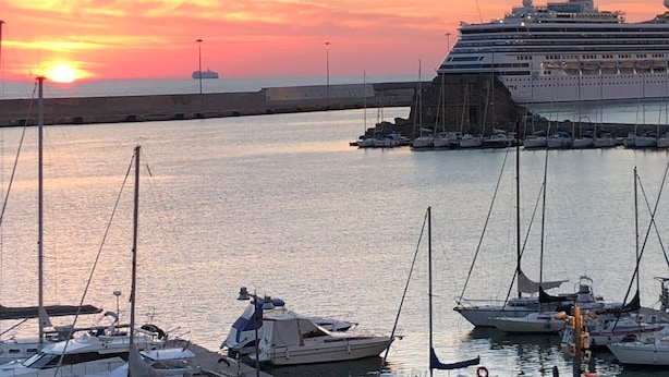 Un crucero amarrado en una marina, con varios veleros cerca.