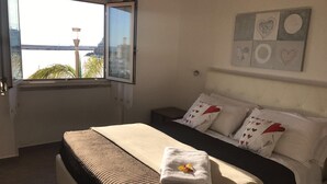 Un dormitorio con cama, ventana y vista a la ciudad.