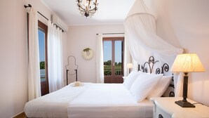 A bedroom with a bed, bedside table, lamp, and a view of the outdoors. - Aeriko-Varko Beachfront Villa with Stunning View and Private Pool (LEFKADA)