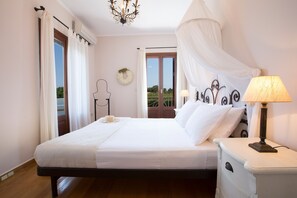 A bedroom with a bed, bedside table, lamp, and a view of the outdoors. - Aeriko-Varko Beachfront Villa with Stunning View and Private Pool (LEFKADA)